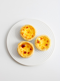 白色碟子上摆放着的早餐美食蛋挞