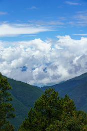 蓝天上连绵的白云山峰和前景的树木
