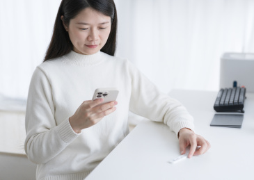 女人看着手机手拿抗原测试盒在上传检测结果