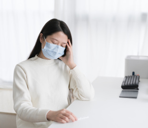 穿白色毛衣的女人手撑着头坐在桌前