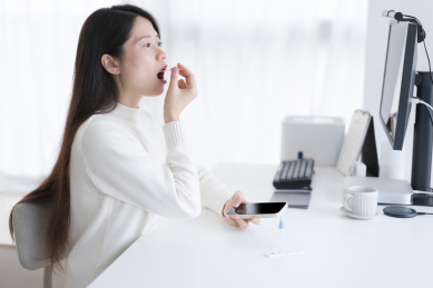 穿白色毛衣的女人张开嘴巴在做抗原检测