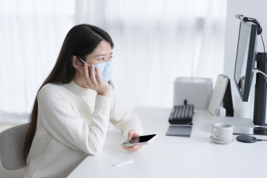 戴着口罩的女人坐在办公桌前思考