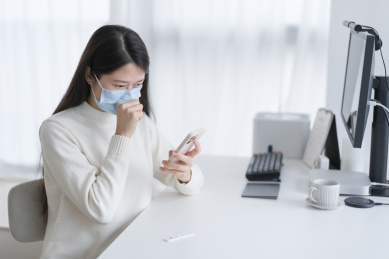 戴着口罩咳嗽的女人手拿手机在上传测试结果