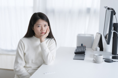 穿白色毛衣的女人手托腮无精打采的坐着