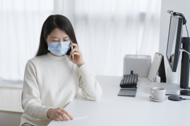手拿抗原测试盒的女人在使用手机通话中