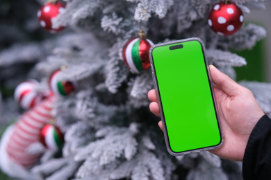 圣诞节时手拿绿色屏幕的智能手机