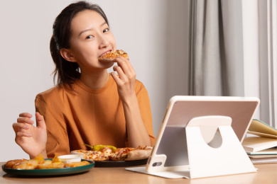 一边使用平板电脑一边吃东西的年轻女人