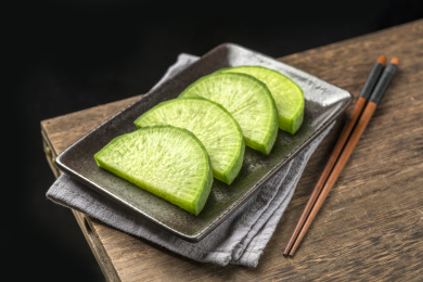 一盘青萝卜片摆放在木桌面背景上特写