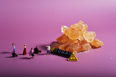 紫色背景上的冰糖和微缩小人偶关于糖与健康