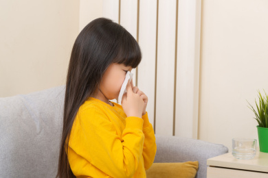 被传染新冠的小女孩低头拿纸巾擦鼻涕