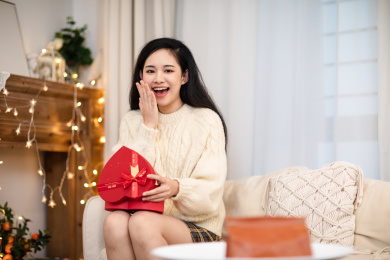 穿着白色衣服的女生看着手中的礼物表情惊讶