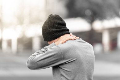 男子在户外捂住脖子，疼痛示意