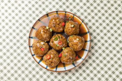 一盘红烧丸子摆放在格子桌布上特写蓝色背景