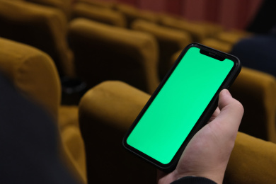 在电影院手拿着绿屏智能手机的特写