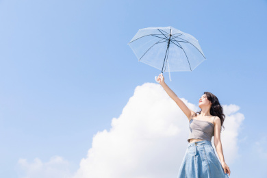蓝天白云下撑伞的中国年轻女性