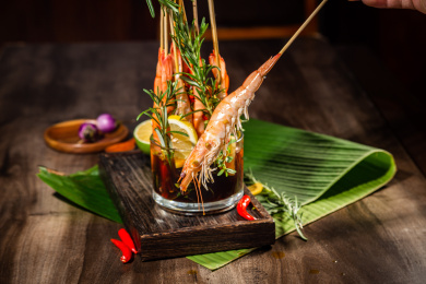 木纹桌面上有一把竹签生腌酸辣虾