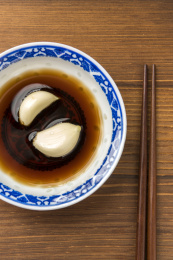 泡着大蒜瓣的醋碟摆放在木桌面上特写