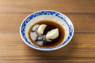 泡着大蒜瓣的醋碟摆放在木桌面上特写