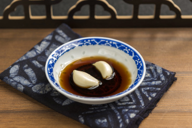 泡着大蒜瓣的醋碟摆放在木桌面上特写