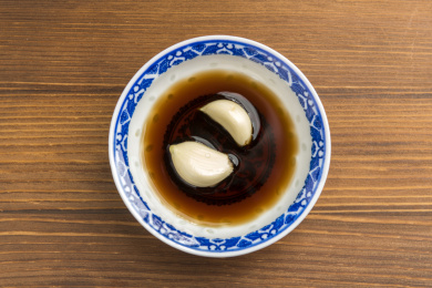 泡着大蒜瓣的醋碟摆放在木桌面上特写