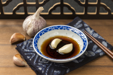 泡着大蒜瓣的醋碟摆放在木桌面上特写