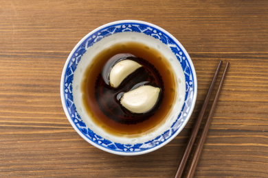 泡着大蒜瓣的醋碟摆放在木桌面上特写