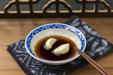 泡着大蒜瓣的醋碟摆放在木桌面上特写