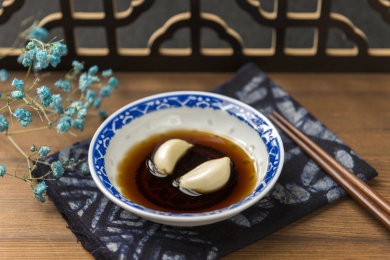 泡着大蒜瓣的醋碟摆放在木桌面上特写