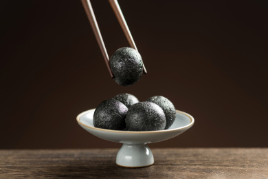 一盘黑芝麻丸摆放在木桌面上特写