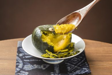 一盘蒸南瓜摆放在木桌面上勺盛蒸南瓜特写