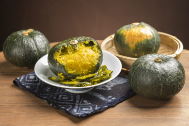 一盘蒸南瓜摆放在木桌面上勺盛蒸南瓜特写