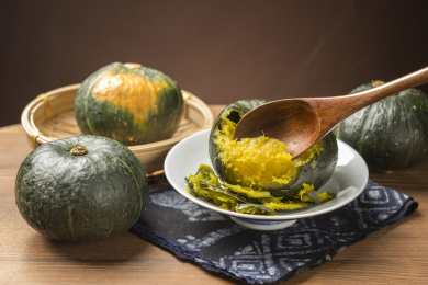 一盘蒸南瓜摆放在木桌面上勺盛蒸南瓜特写