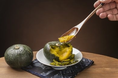 一盘蒸南瓜摆放在木桌面上勺盛蒸南瓜特写