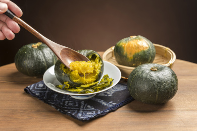 一盘蒸南瓜摆放在木桌面上勺盛蒸南瓜特写