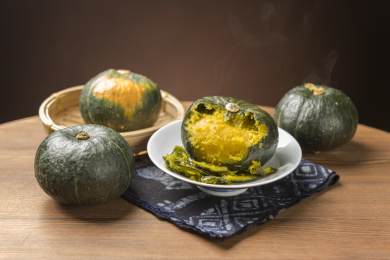 一盘蒸南瓜摆放在木桌面上勺盛蒸南瓜特写