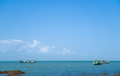 蓝天下海南海口海岸边的渔船捕捞场景