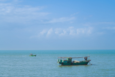 蓝天下海南海口海岸边的渔船捕捞场景