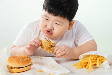 可爱的肥胖小男孩吃炸鸡汉堡