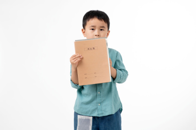 男孩在白色背景下拿着作业本