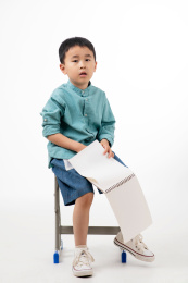 男孩在白色背景下拿着作业本