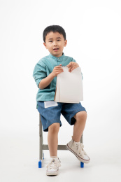 男孩在白色背景下拿着作业本