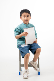 男孩在白色背景下拿着作业本