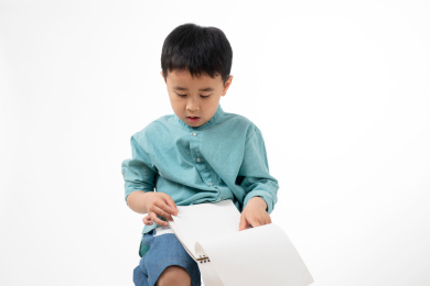 男孩在白色背景下拿着作业本