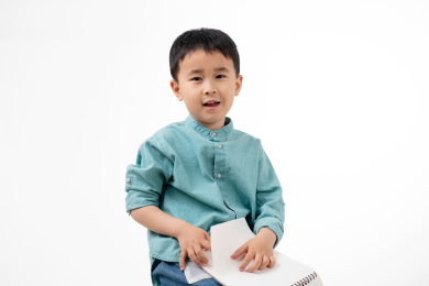 男孩在白色背景下拿着作业本