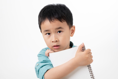 男孩在白色背景下拿着作业本