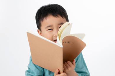 男孩在白色背景下拿着作业本