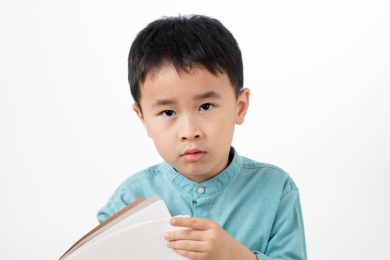 男孩在白色背景下拿着作业本