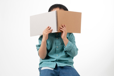 男孩在白色背景下拿着作业本