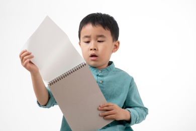 男孩在白色背景下拿着作业本