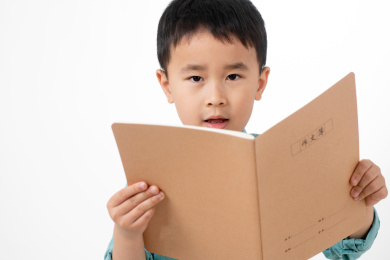 男孩在白色背景下拿着作业本